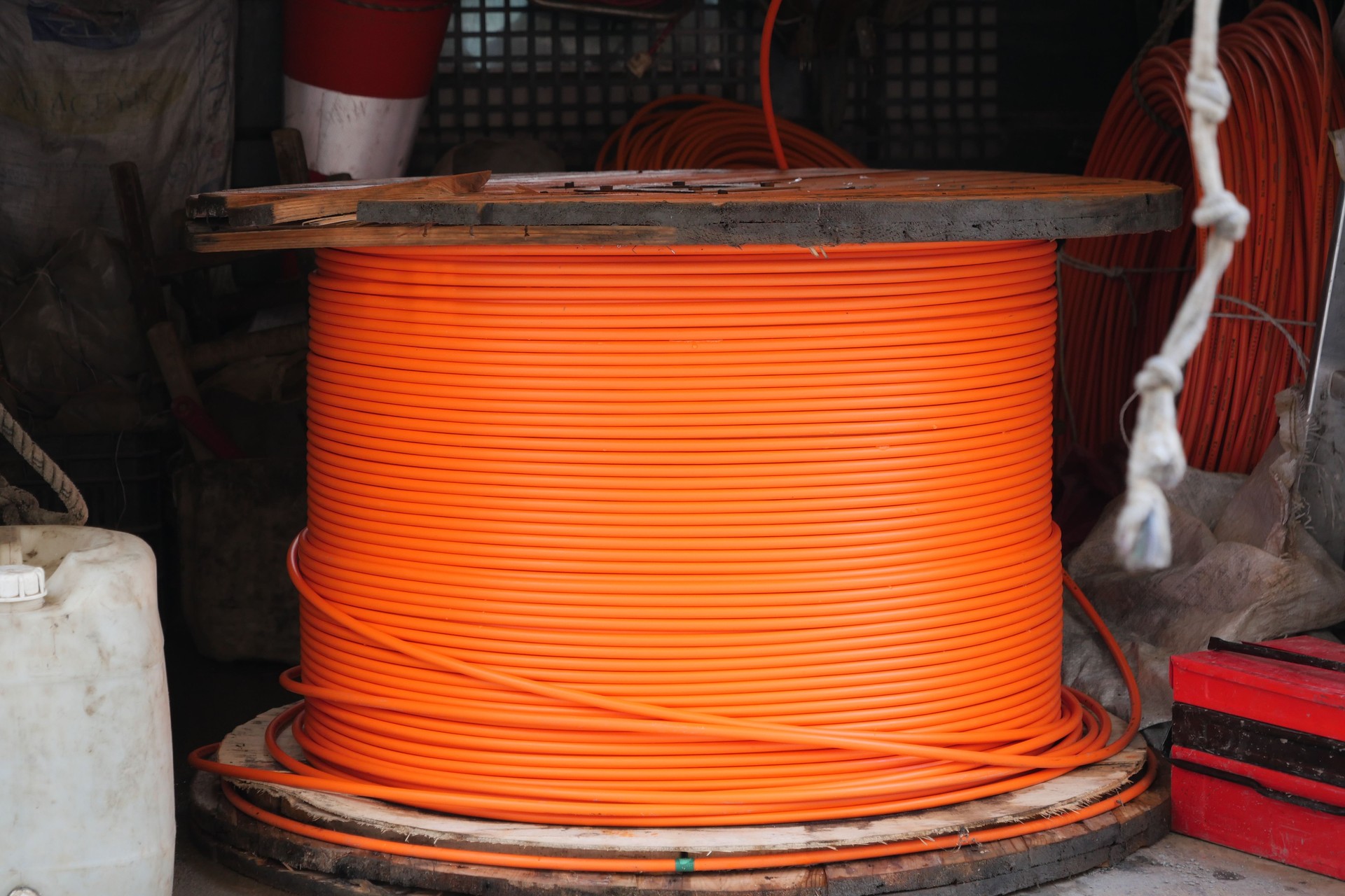 A large orange cable reel is kept in a warehouse for construction and maintenance
